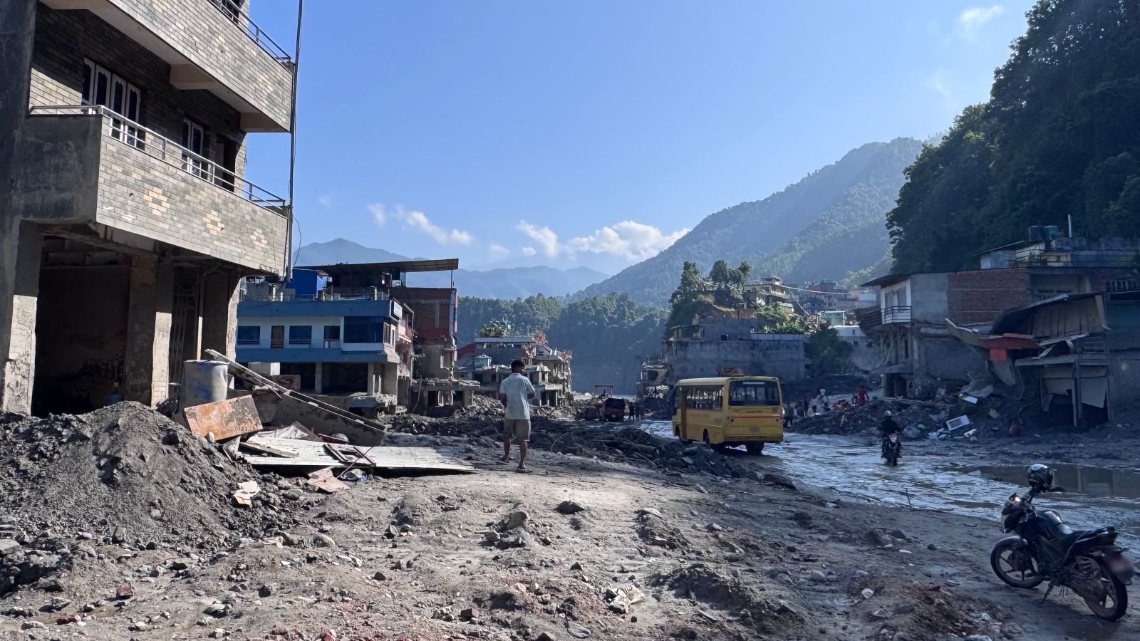 A street lined with damaged buildings, covered in mud and debris after the flood.