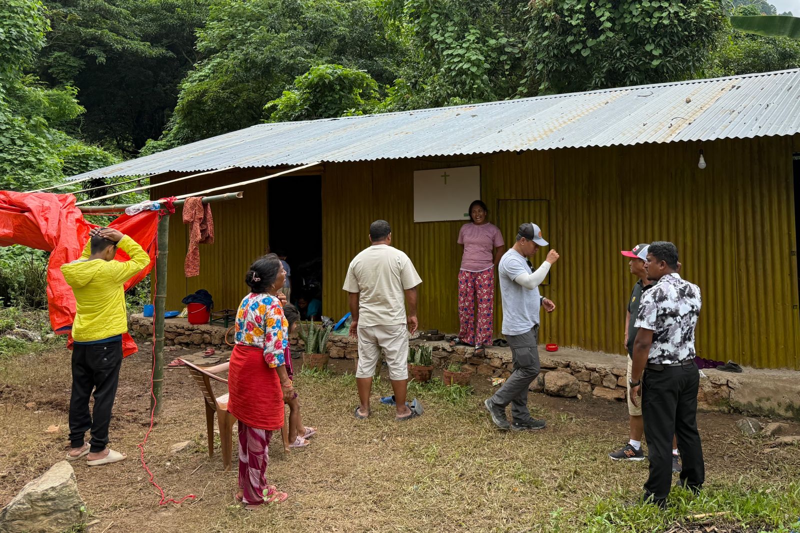 A group of people standing outside a church with a metal roof.