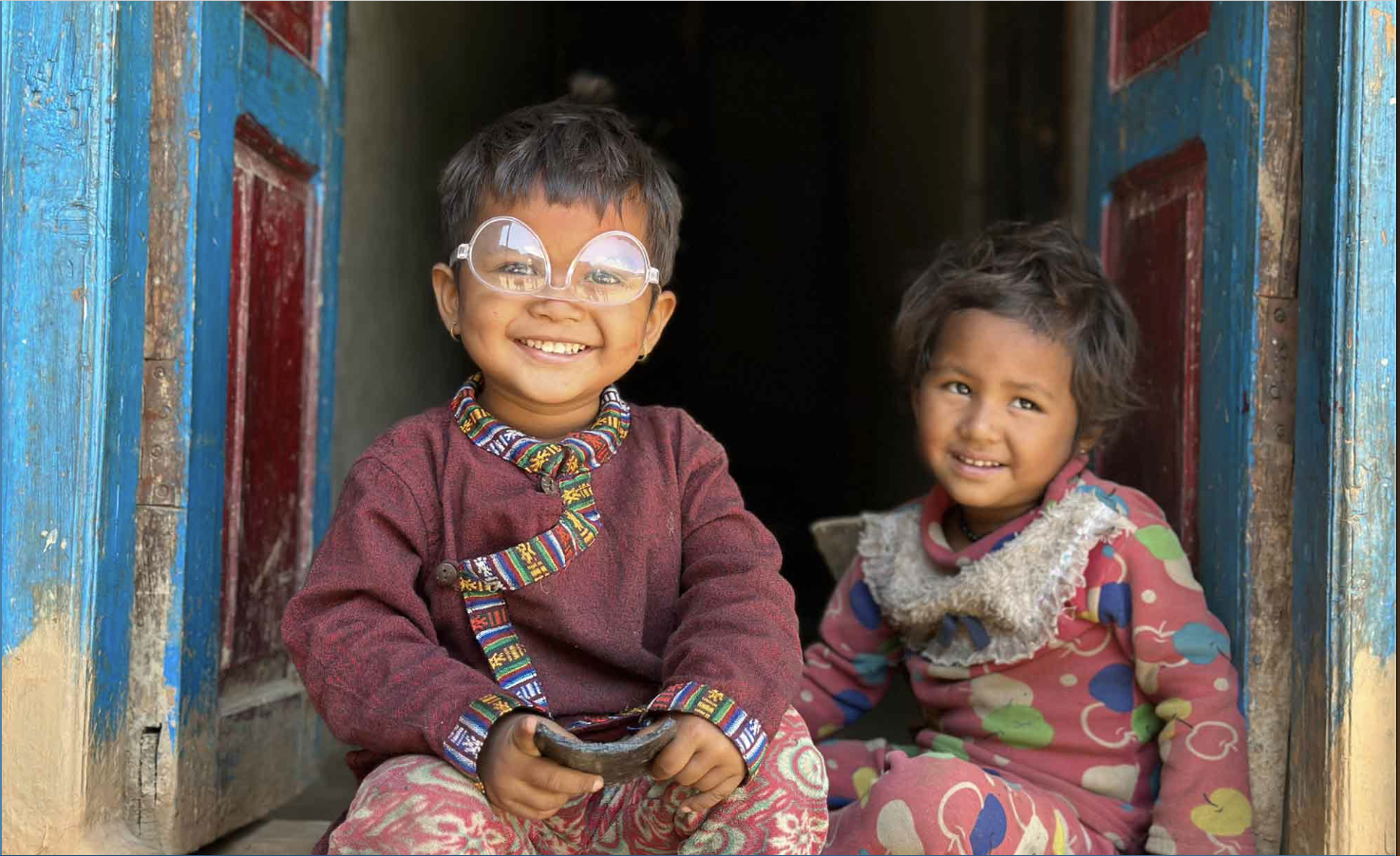 Niños sonriendo en una puerta, atendidos a través de Commissioned International